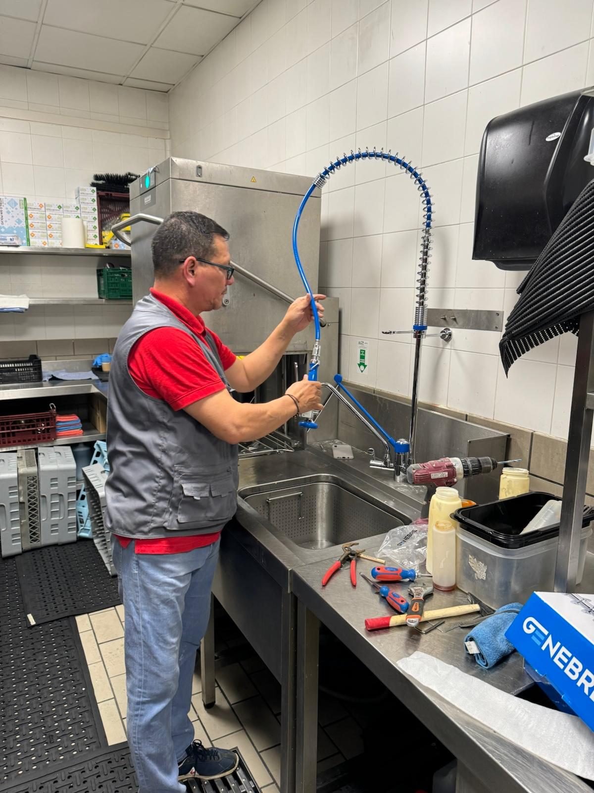 Técnico de Servihogar reparando fontanería en una cocina profesional